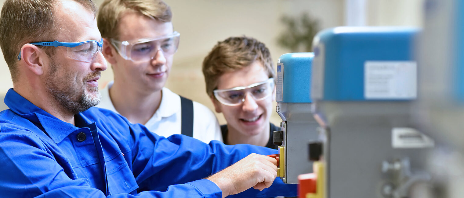 Group of young people in mechanical vocational training with teacher at drilling machine